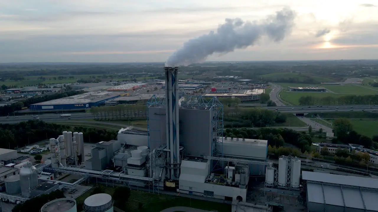 Aerial of smoking factory chimney with an industrial area in the background