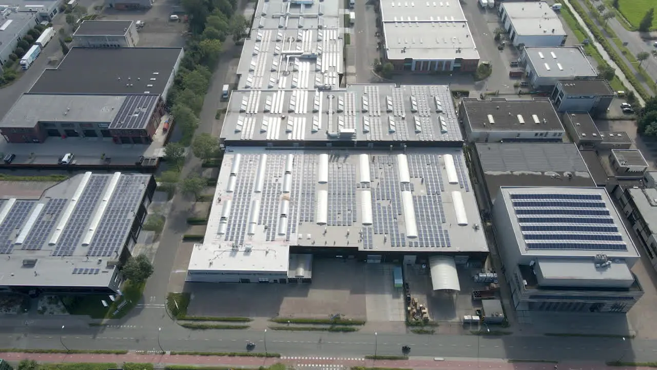 Aerial tilt down to solar panels on rooftop of industrial buildings