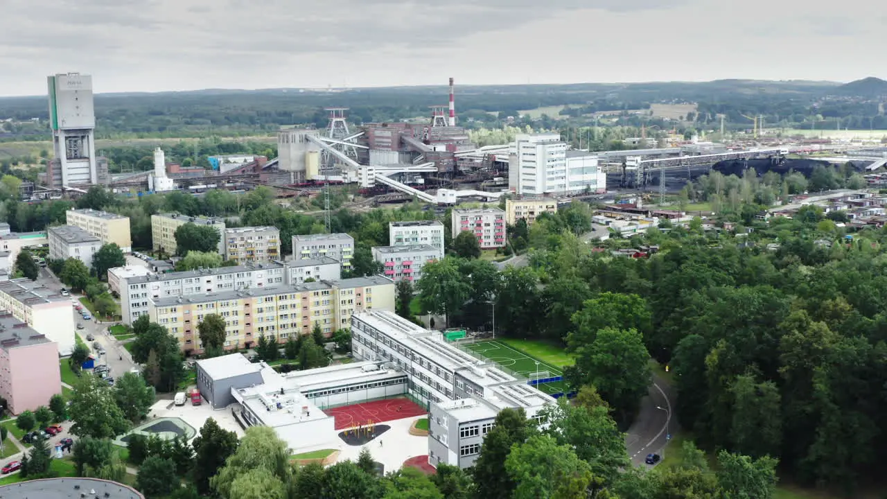 Left orbiting shot a town with elementary school with a brand new soccer field in the foreground and a big old coal mine in the background showing ecological contrast