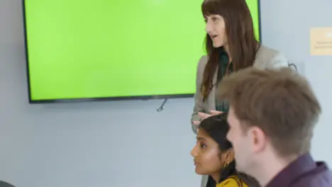 Businesswoman Giving Presentation To Colleagues With Green Screen Tv