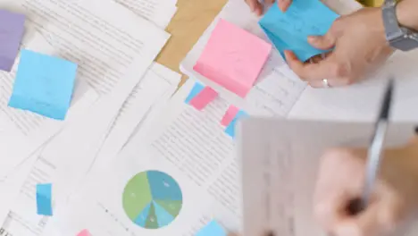 Overhead Of Paperwork And Hands Of Business Colleagues Brainstorming Around Table