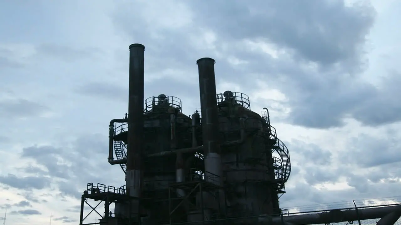 Clouds move across the sky behind an oil refinery