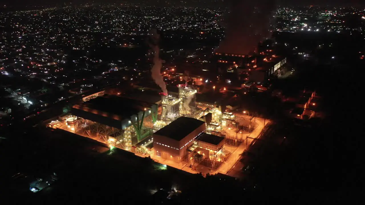 Aerial shot of a working factory in the middle of a Mexican town a few hours before sunrise