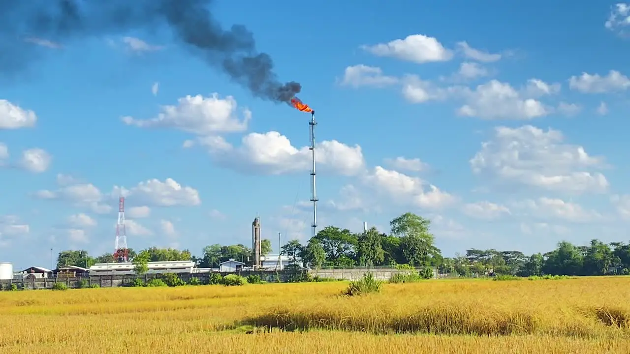 Refinery burning gas plant in rural area with agriculture fields handheld view