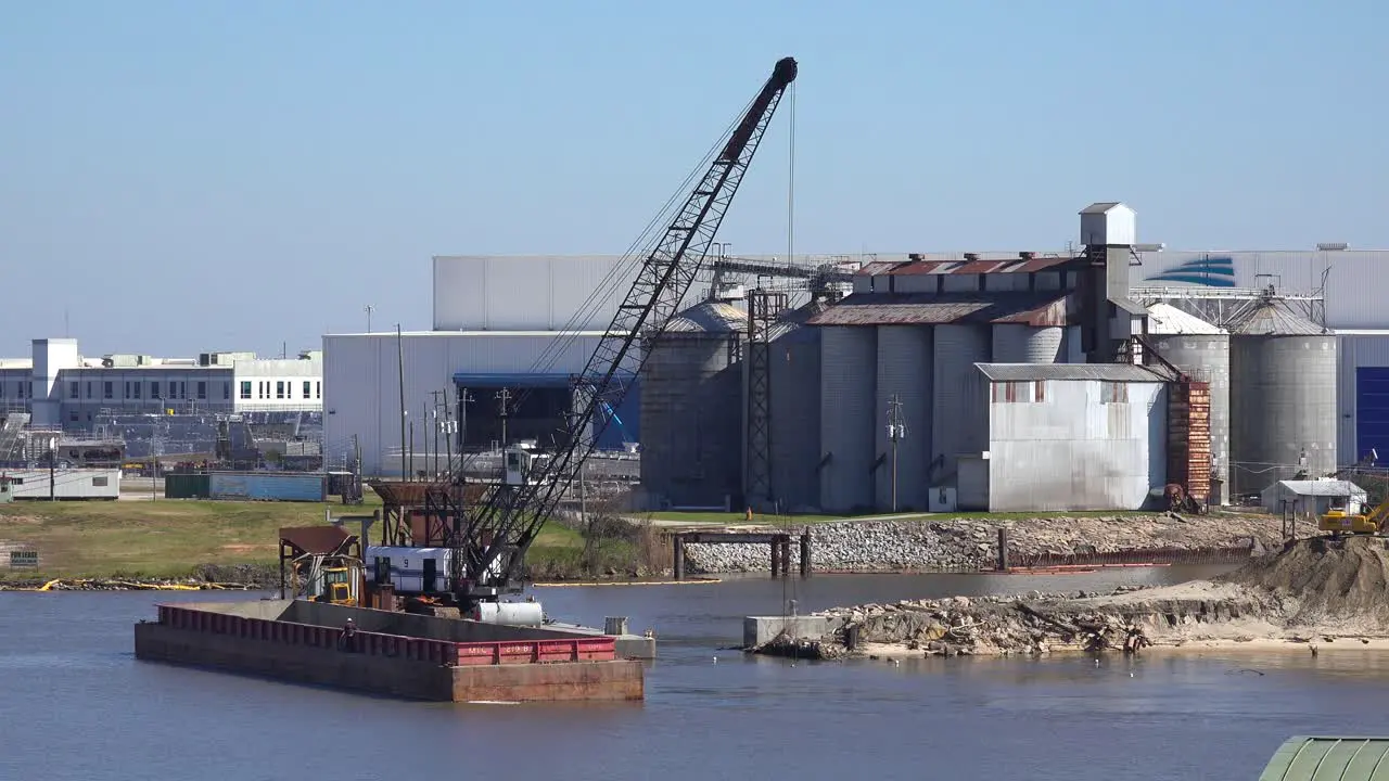 A large crane sitting on a barge dredges a harbor