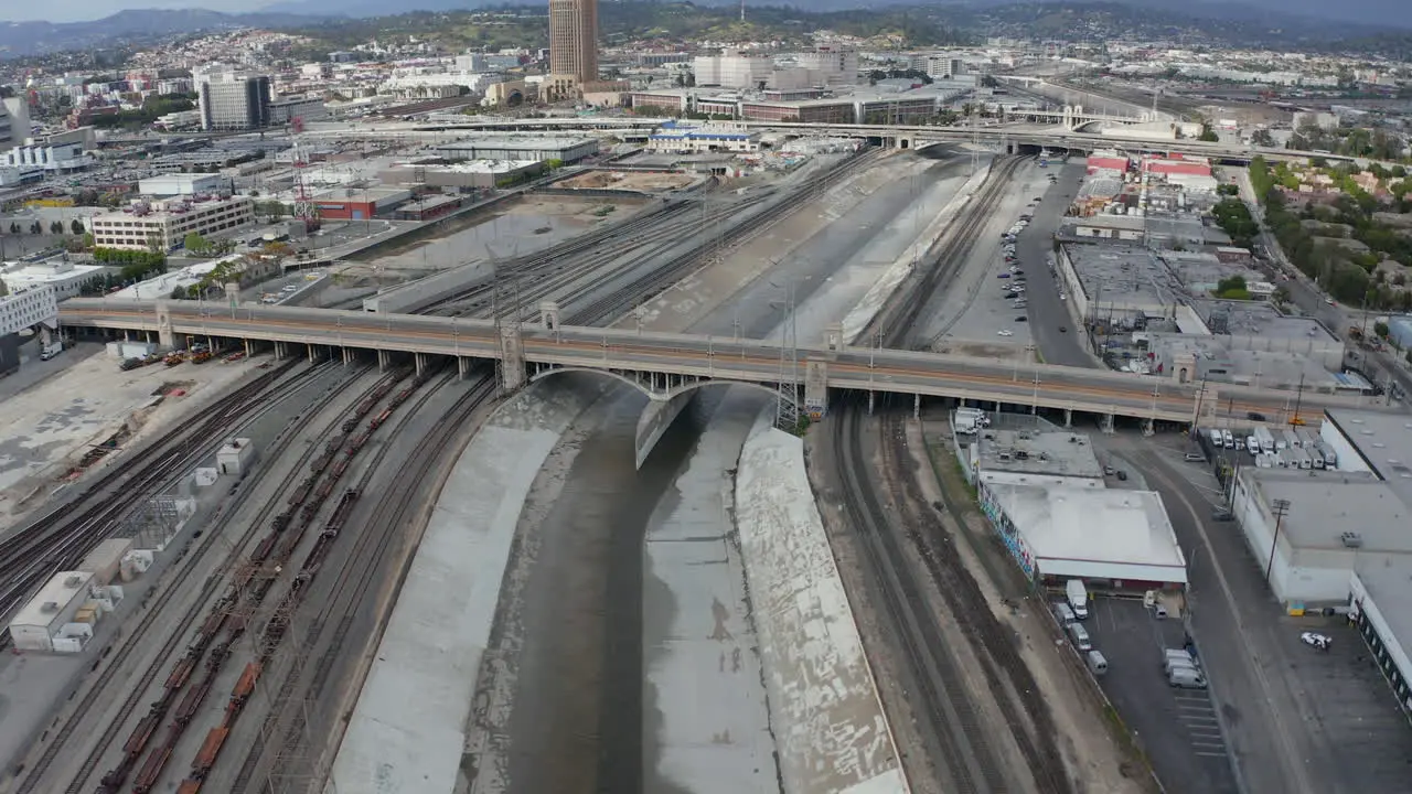 AERIAL Los Angeles River Bridge with Tram Train Crossing on Cloudy Overcast Sky