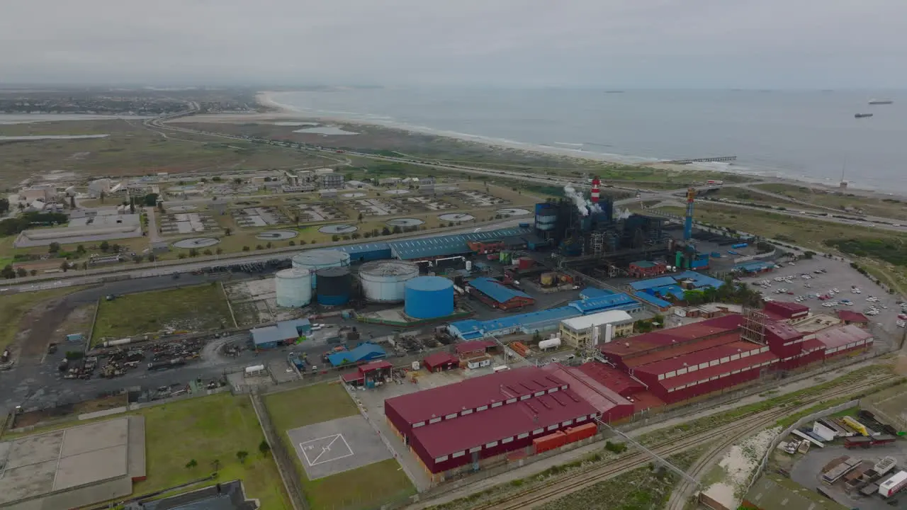 Aerial footage of industrial site on seaside Factory with striped chimneys and production halls near coastal highway Port Elisabeth South Africa