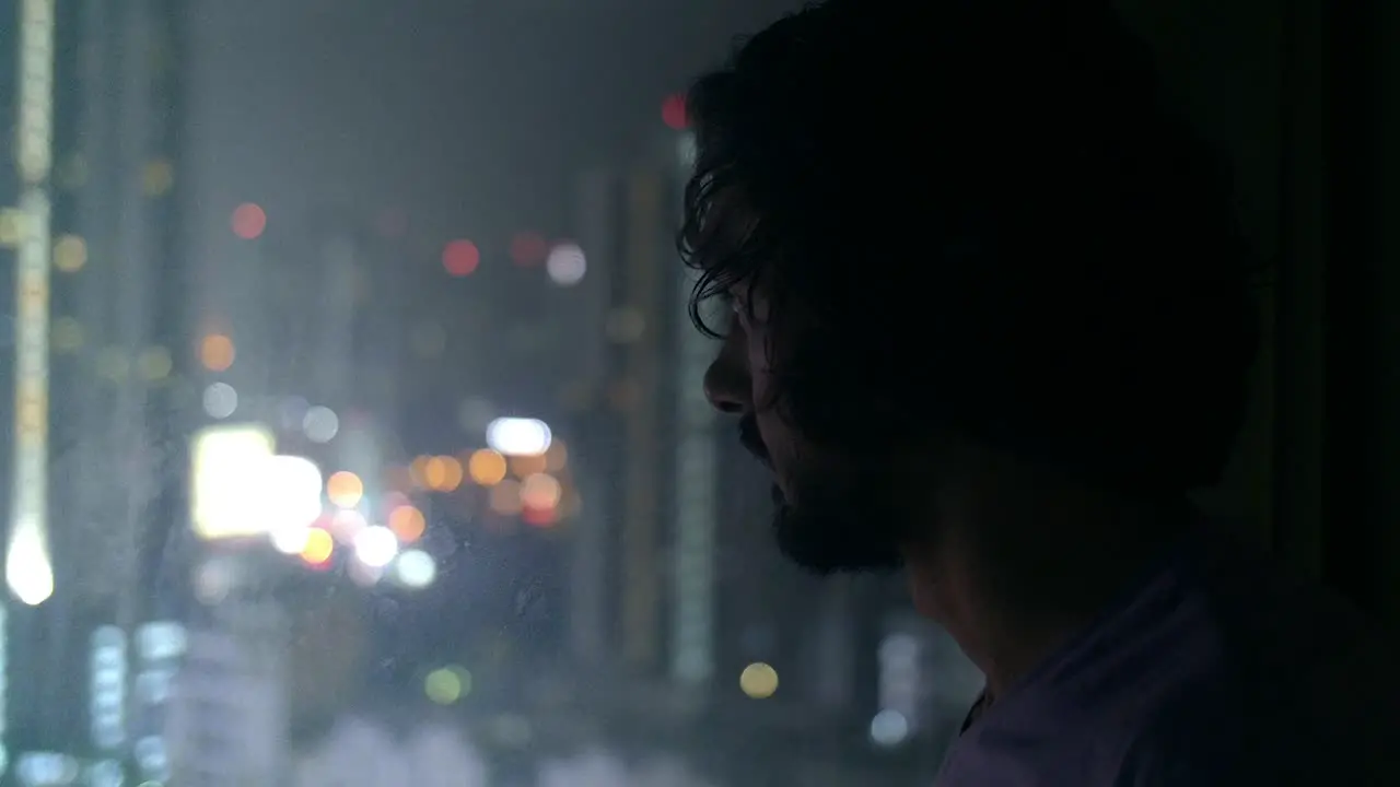 Man Looking Out of City Window at Night