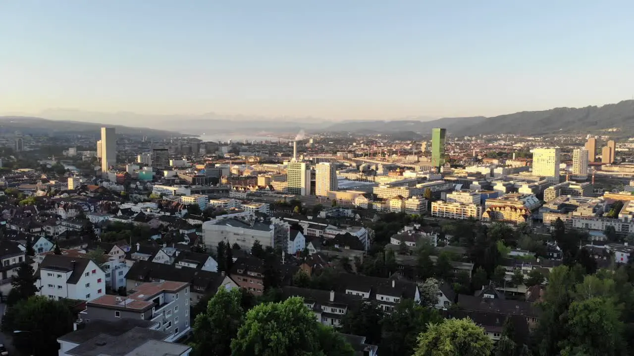 Drone flying backwards above Zürich city at sunrise 4k