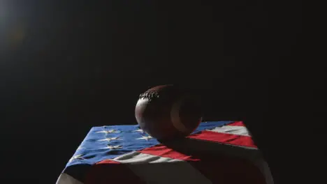 Low Key Lighting Studio Shot Of American Football On Stars And Stripes Flag 1