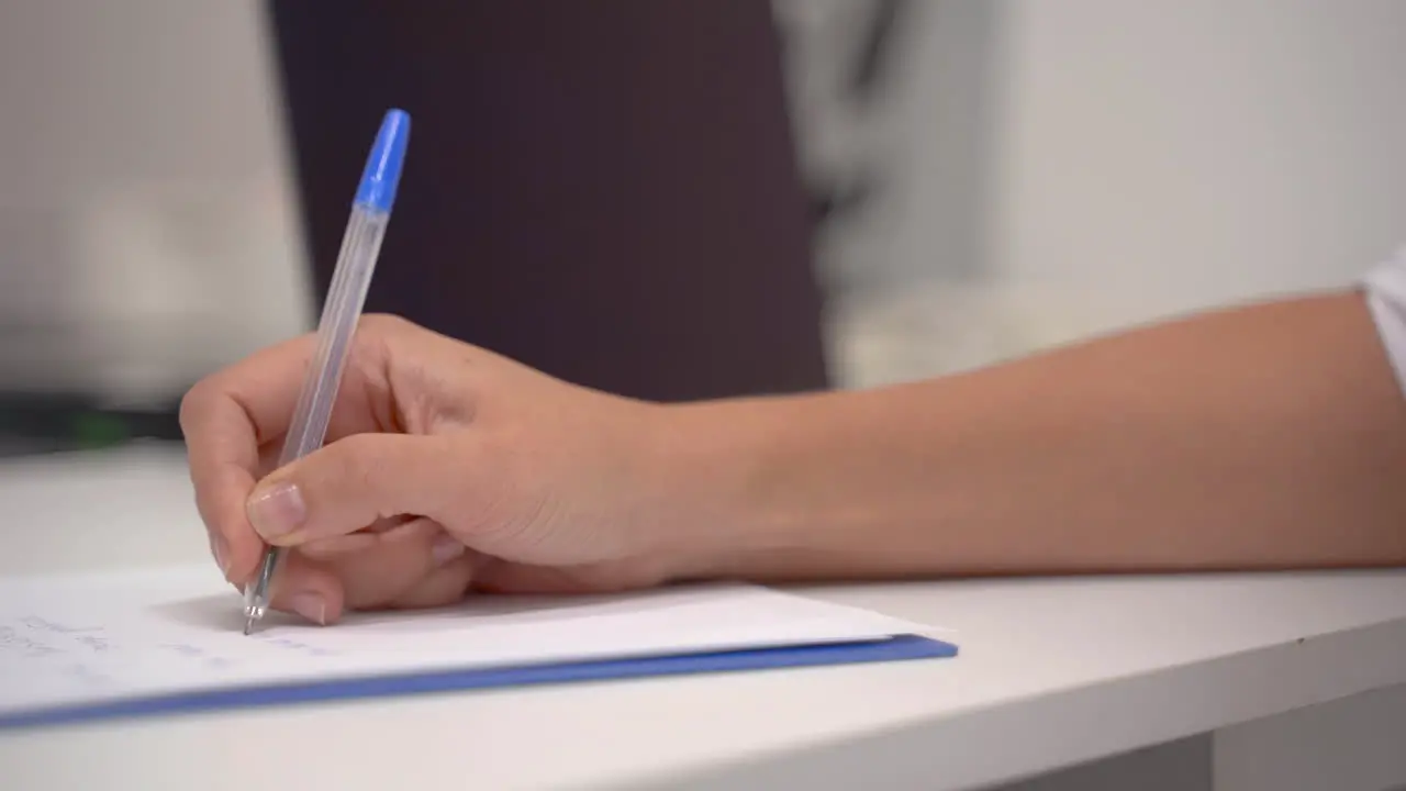 Close Up Of The Hand Of A Female Doctor Writing The Symptoms And Prescription Of A Patient In Her Office