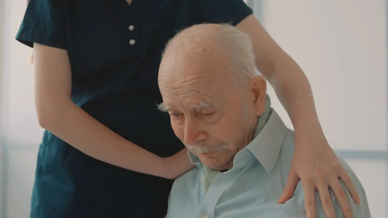 Portrait Of Emotional Sad Elderly Man Caring Nurse Cheering Up