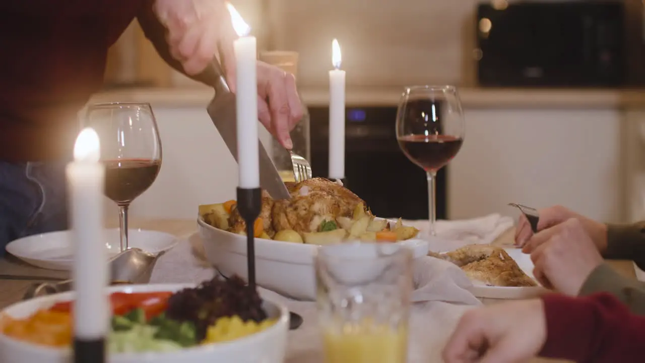 Camera Focuses On Man's Hands Cutting The Turkey In Christmas Family Dinner