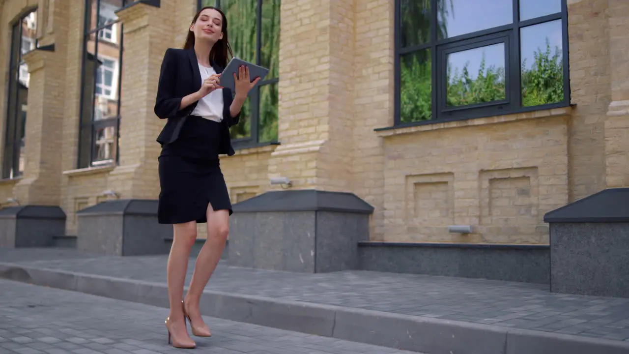 Businesswoman walking to work Suit lady using digital tablet on city street