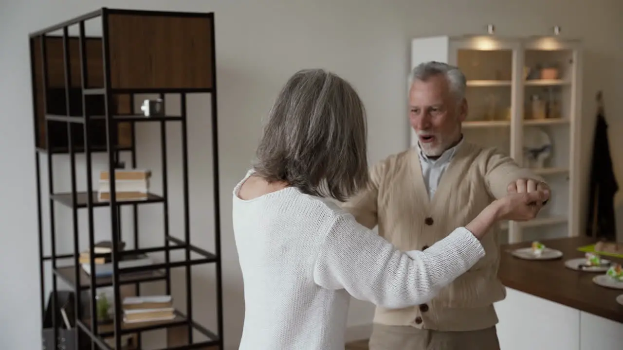 Happy Senior Couple Dancing And Hugging At Home