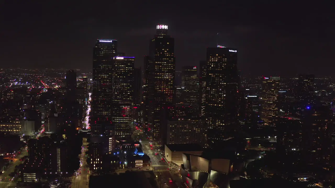 AERIAL Flying into Downtown Skyscrapers Skyline Los Angeles California at Night with City Lights 