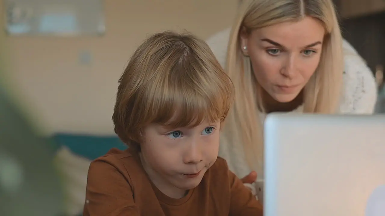 Little Boy Having Online Class With Laptop At Home Mother Helping