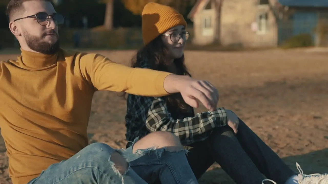 Young female and male friends sharing moments sitting on the beach