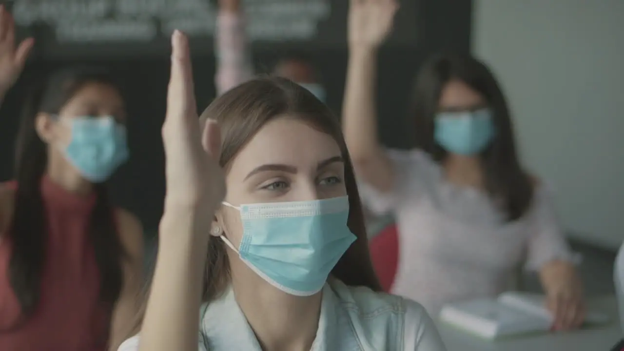 Pretty Student Girl In A Facemask Raises Her Hand In Class