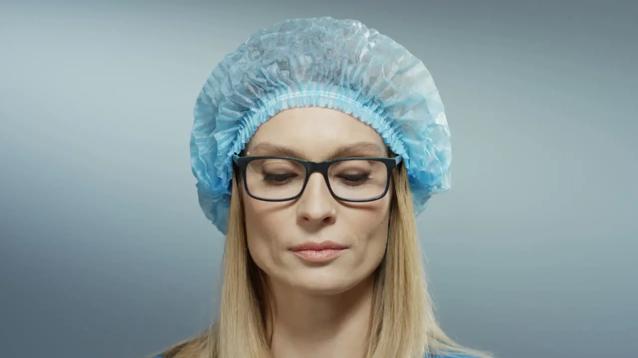 Close Up Of The Young Blond Good Looking Woman Doctor With Serious Face In Blue Hat And Glasses Looking At The Camera