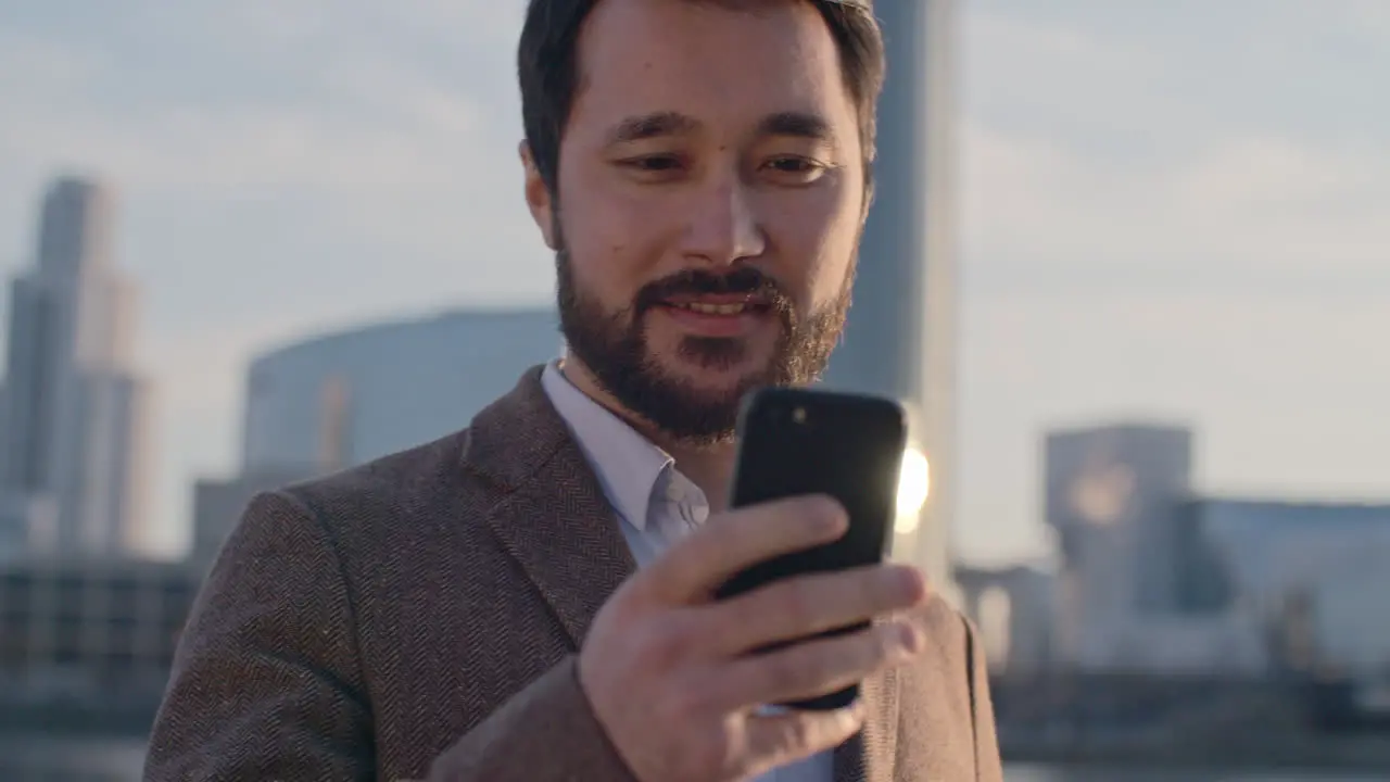 Man Using His Smartphone On A Terrace With Blurred View Of City Buildings