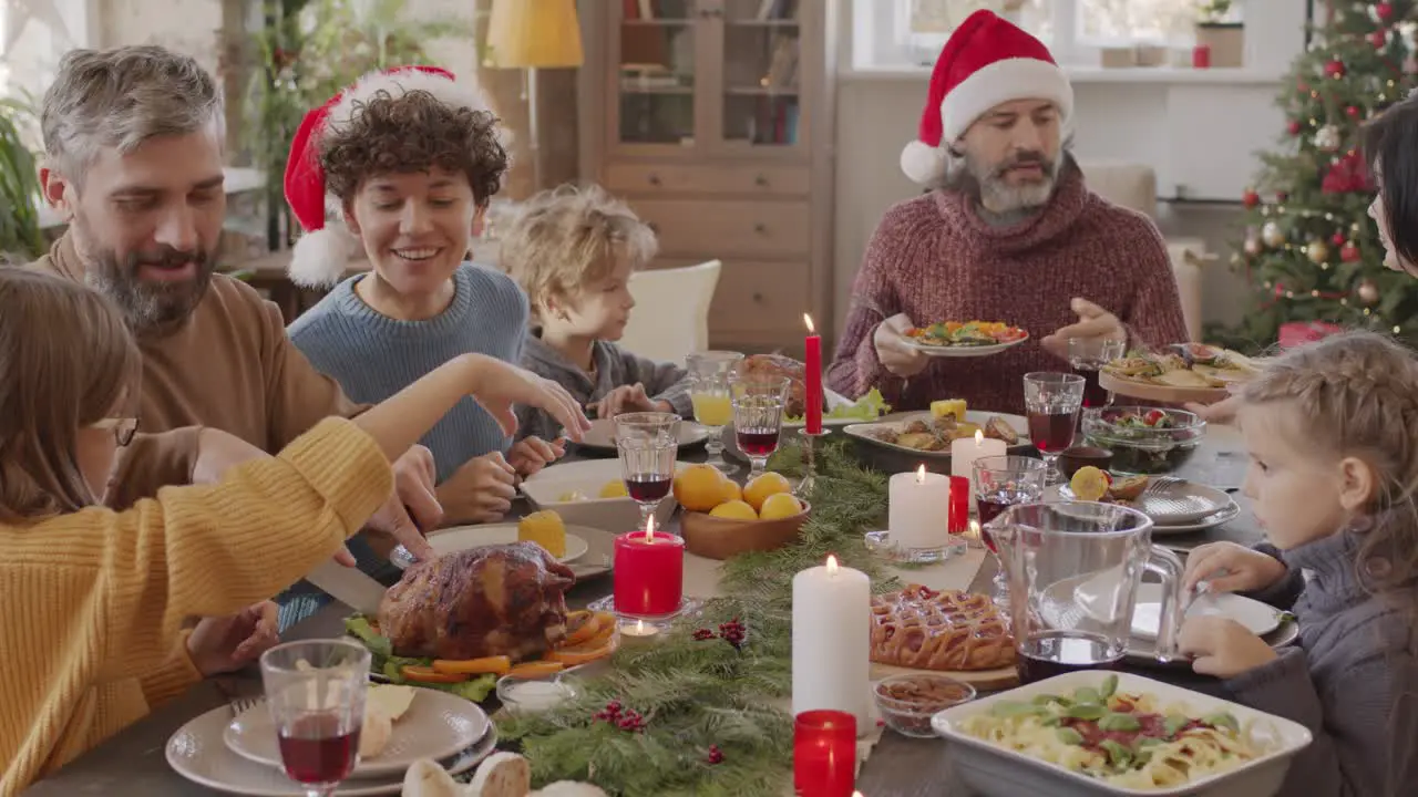 Family Sitting At Table At Christmas Meal They Pass Dishes To Each Other And Talk