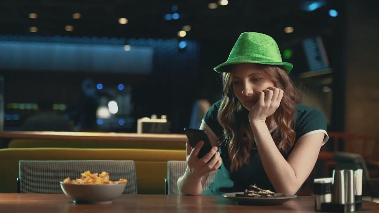 Pretty Young Woman Waiting For Someone Worried Looking At The Phone And Wearing An Irish Green Hat