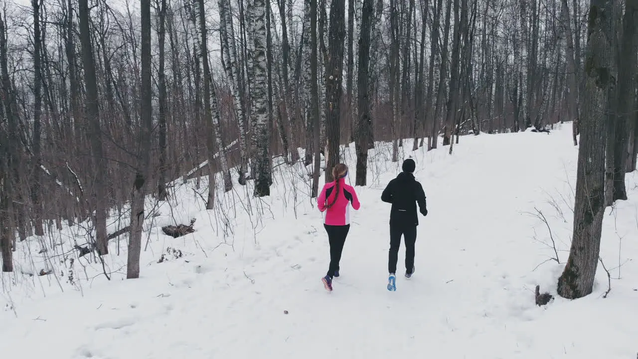 Man and woman in the winter running through the Park in slow motion