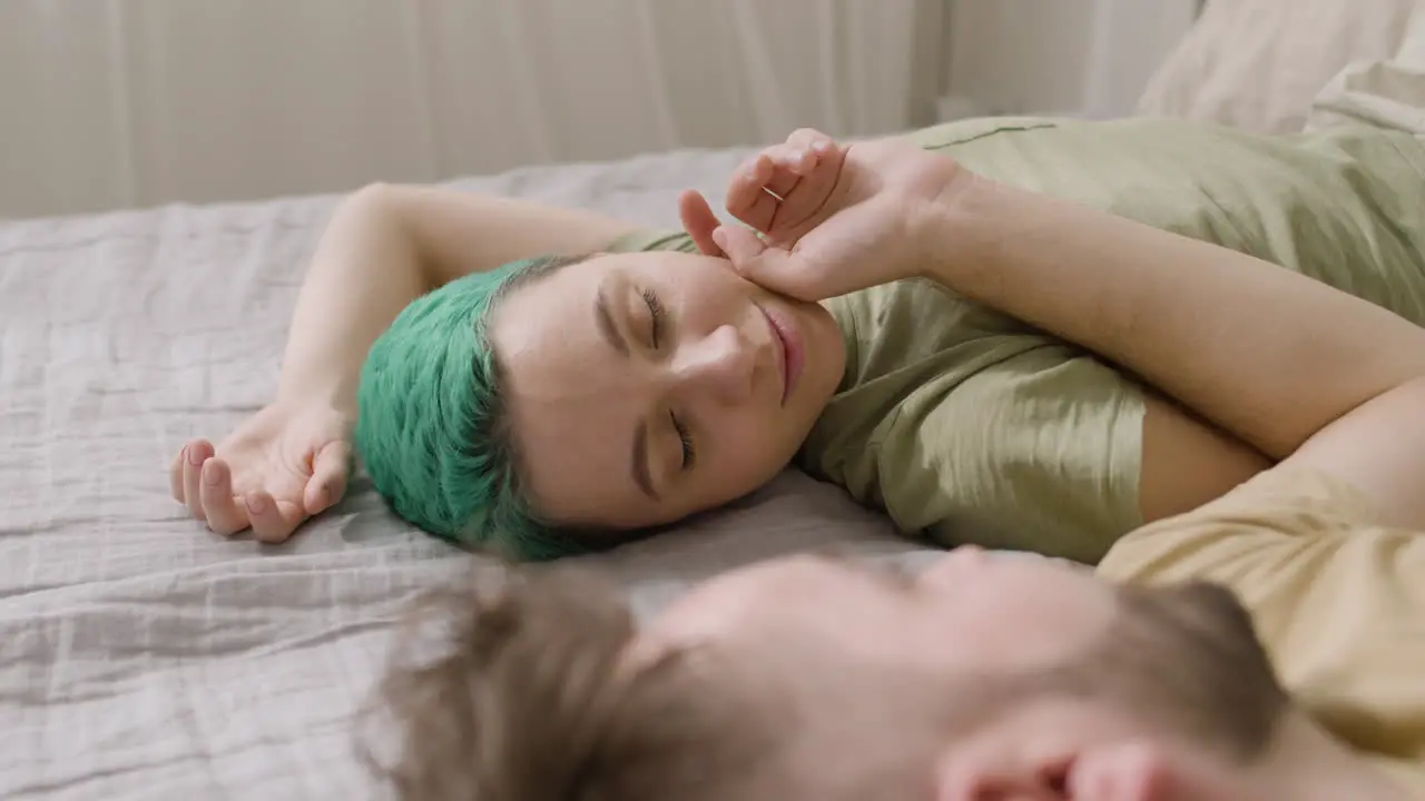 Man Touching His Girlfriend's Cheek While Lying On The Bed At Home