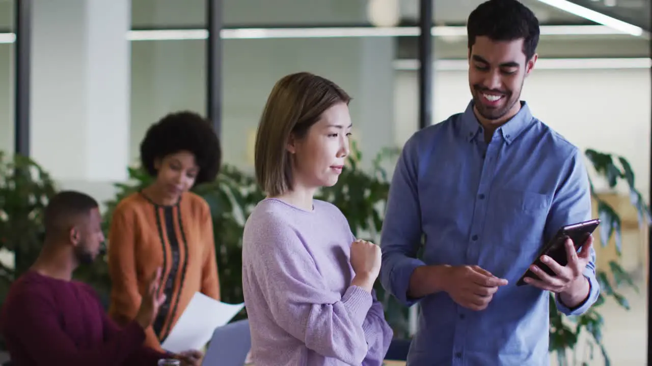 Diverse business people talking using a digital tablet in modern office