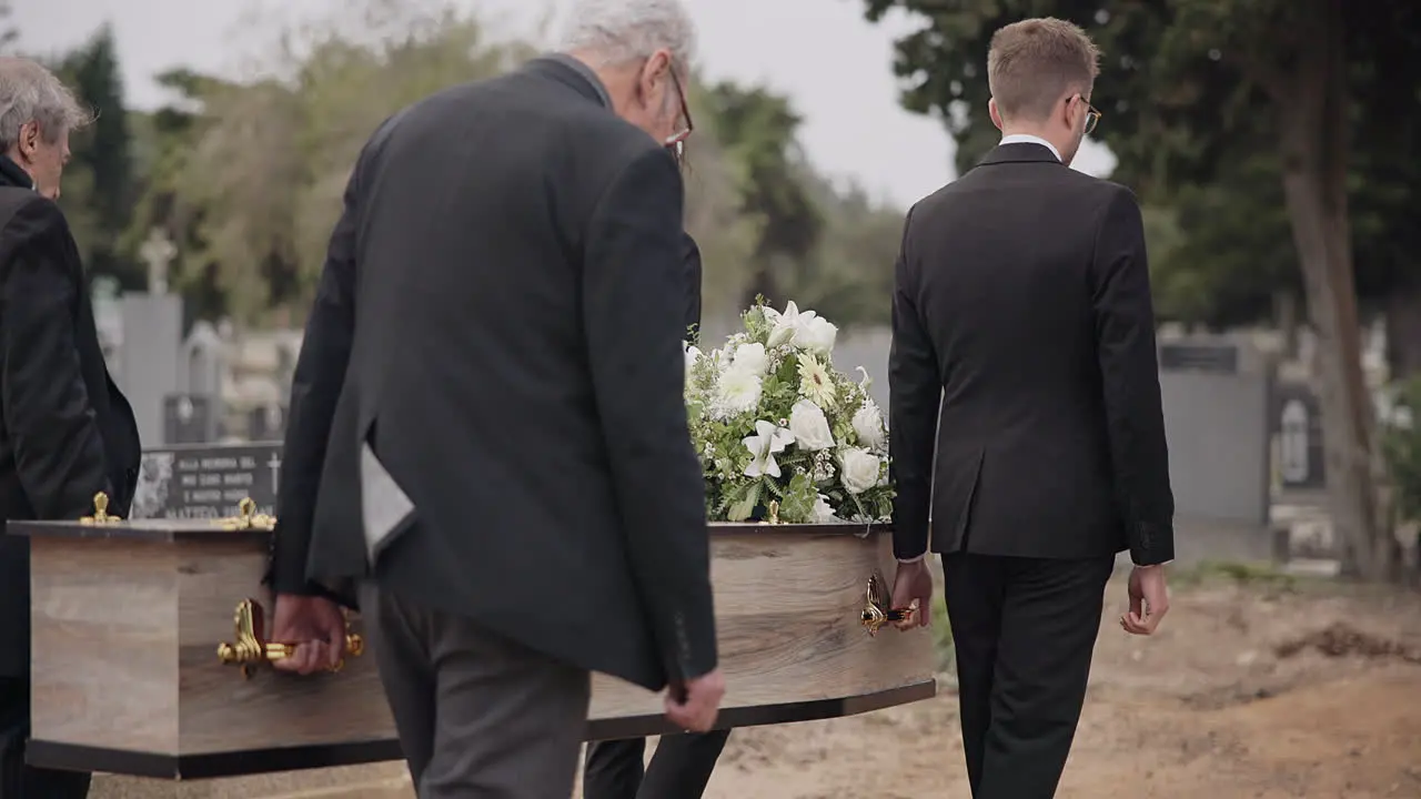 Coffin men and pallbearers walking at graveyard