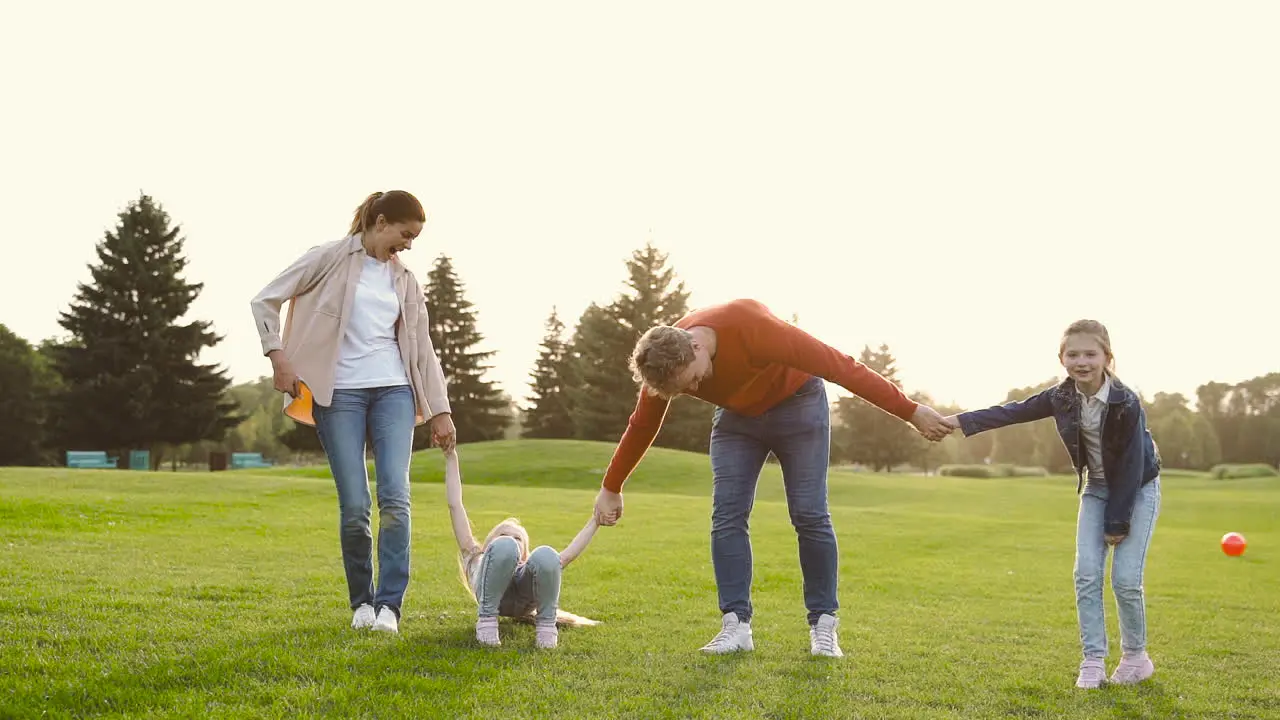 Happy Family Holding Hands And Jumping Together In The Park