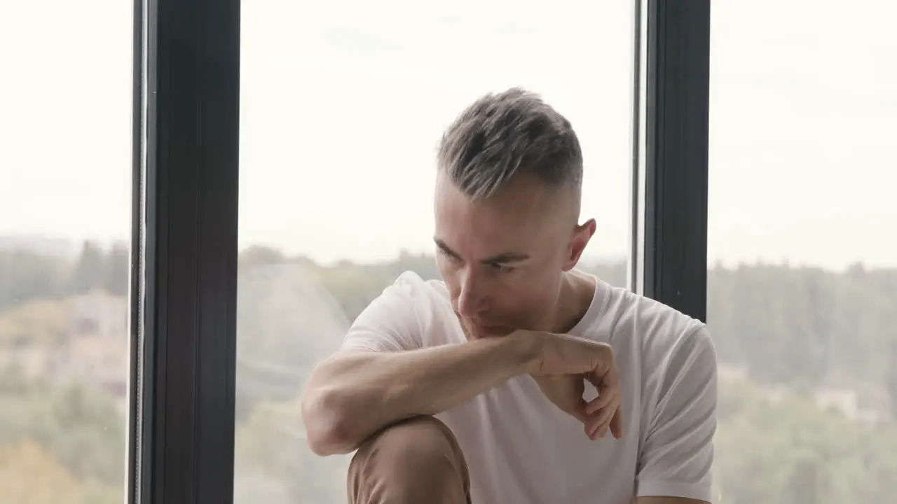 Sad Man Sitting At Window Worrying About Something