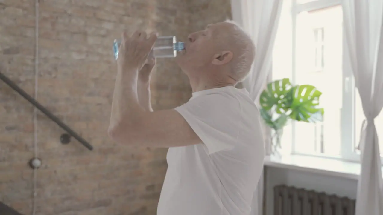 Old Male Drinks Water And Rests After Exercising And Stretching At Home