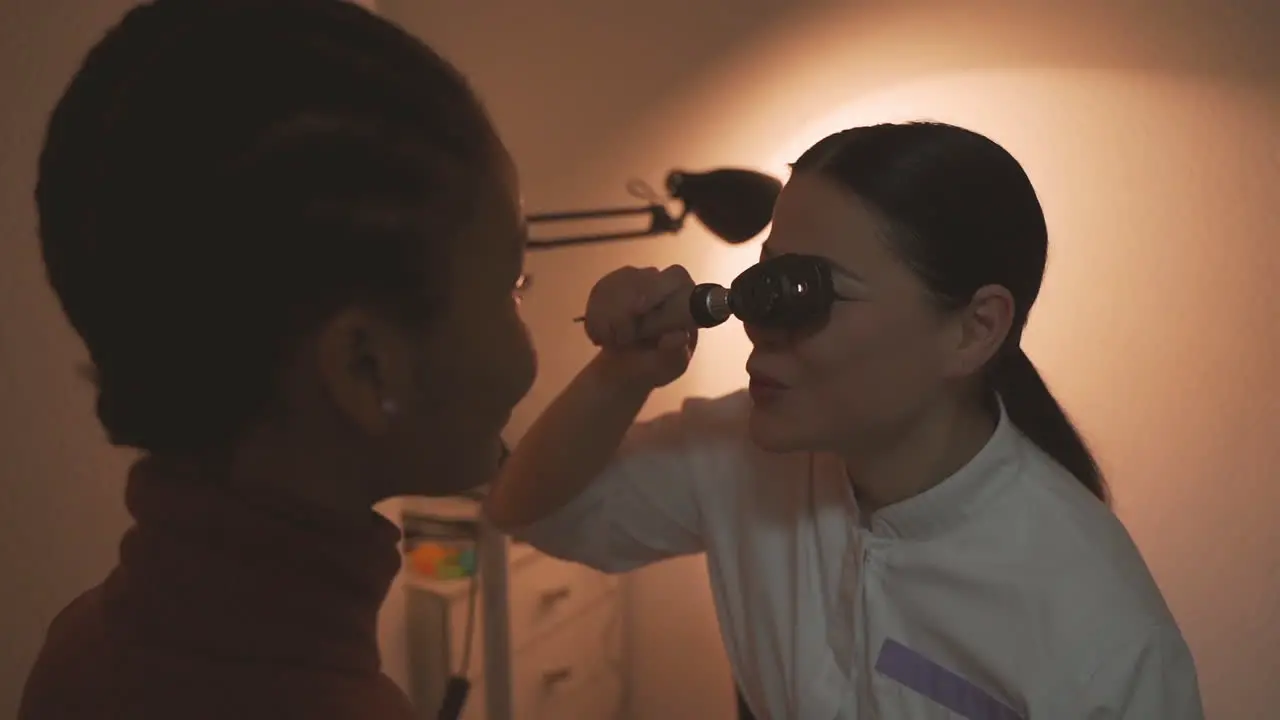 Female Eye Specialist Does Vision Test On Young Girl With Magnifying Lens