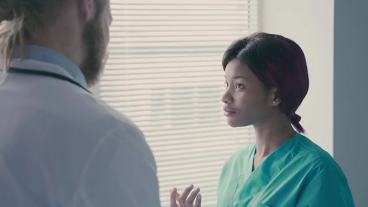 A Cute Young American Nurse Talks With A Young Doctor With Long Blond Hair