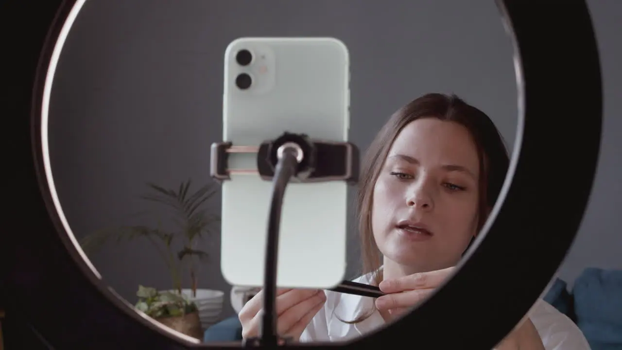 Close Up Of A Pretty Vlogger Female Making A Video Review Of A Make Up Brush Talking Directly To Her Smartphone's Camera