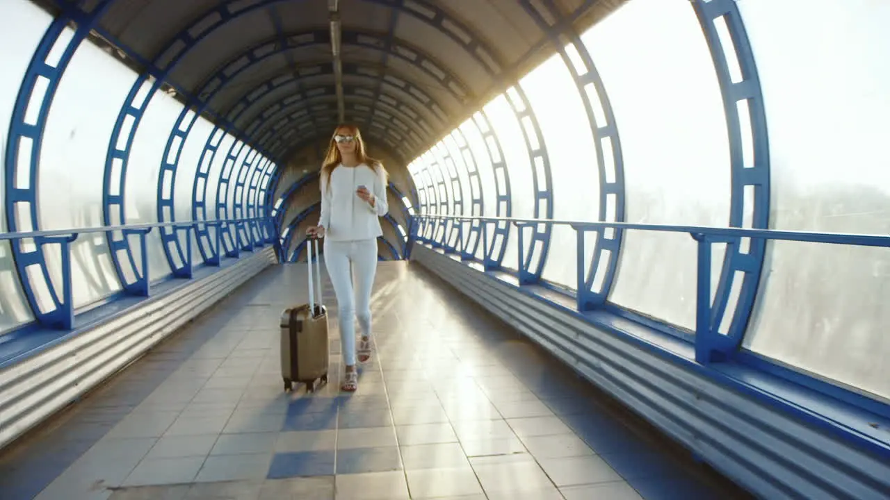 Steadicam Shot Life In Motion Stylish Woman With Travel Bag Is On The Sunlit Move Between Terminals