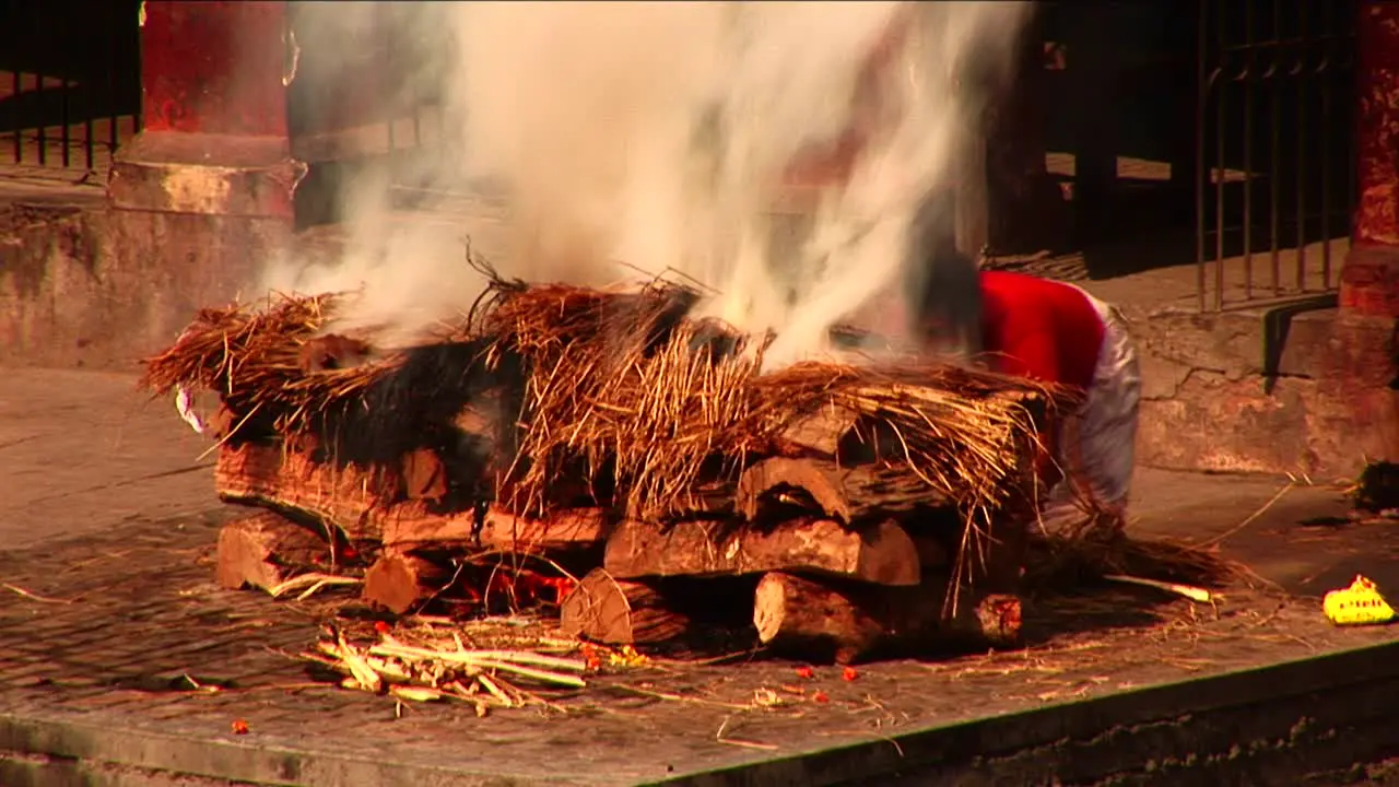 Man stoking large ceremonial fire