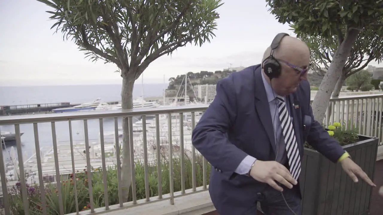 A Businessman In A Suit Dances On The Street With Headphones And A Group Of Young People In Monaco