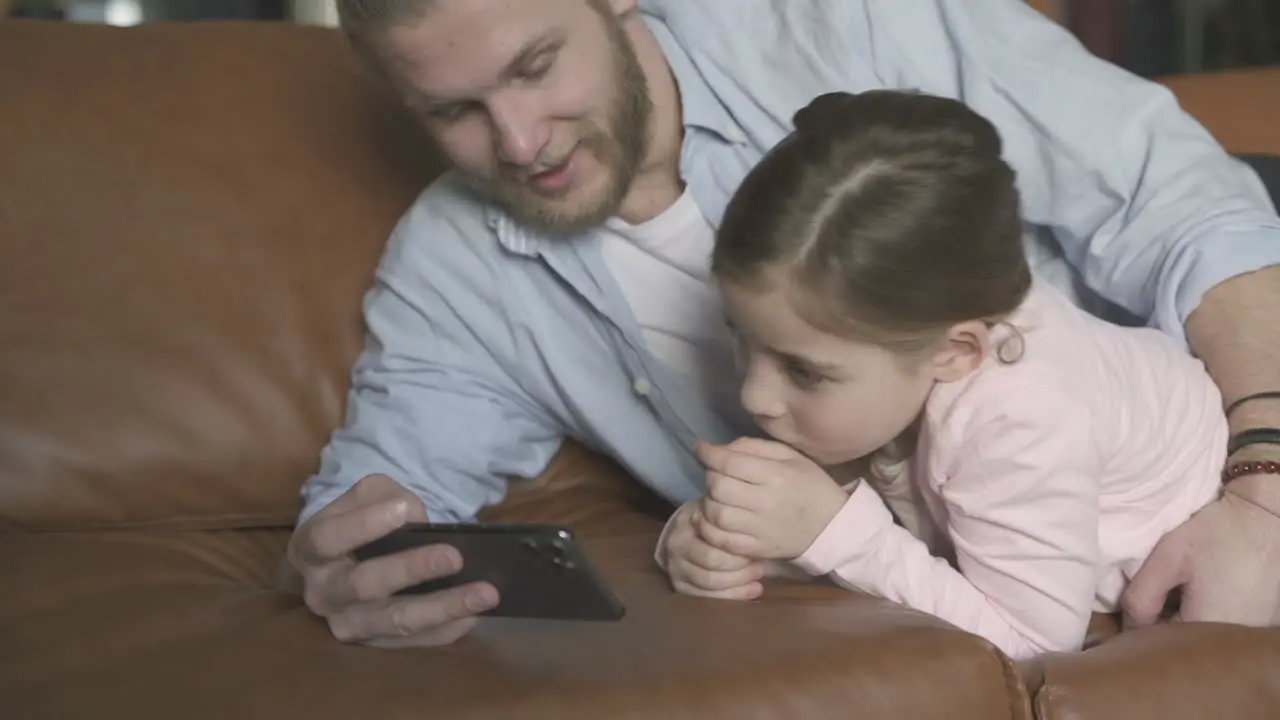 Man And Daughter Watching A Smartphone At Home