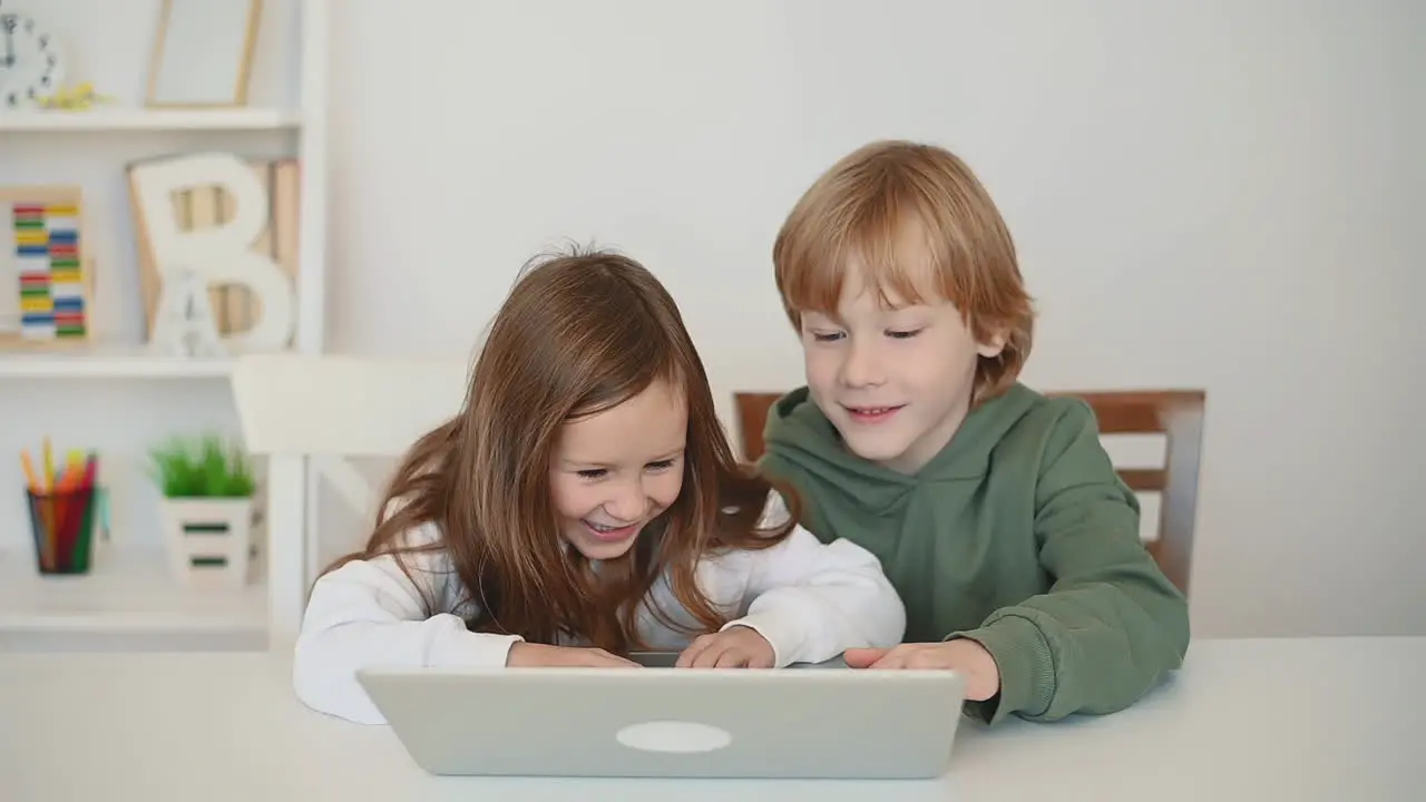 Little Boy And Girl Using A Laptop And Having Fun At Home