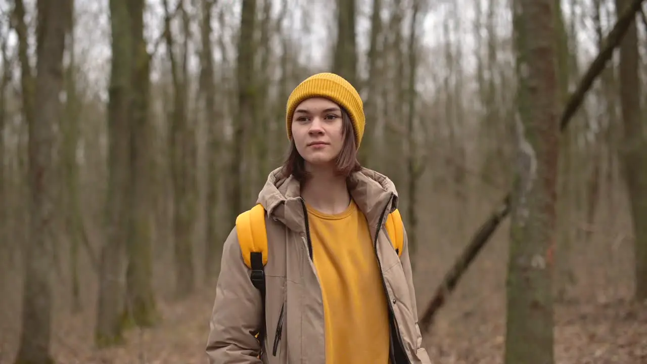 A Young Girl In A Yellow Woolen Hat Walks Through The Forest Looking From Side To Side