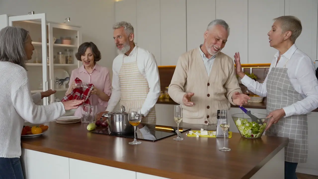 Group Of Older Friends Cooking In The Kitchen While Talking And Laughing