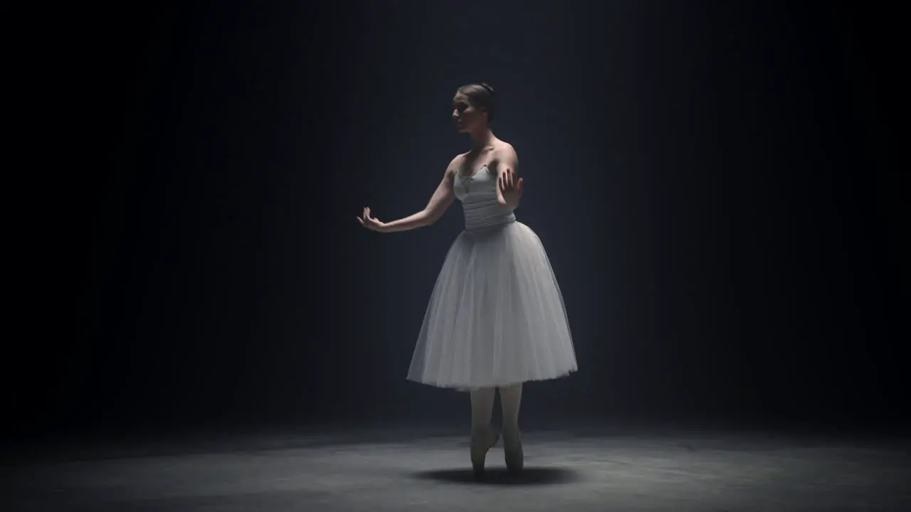 Beautiful ballerina dancing on tiptoe indoors Ballet dancer rehearsing on stage