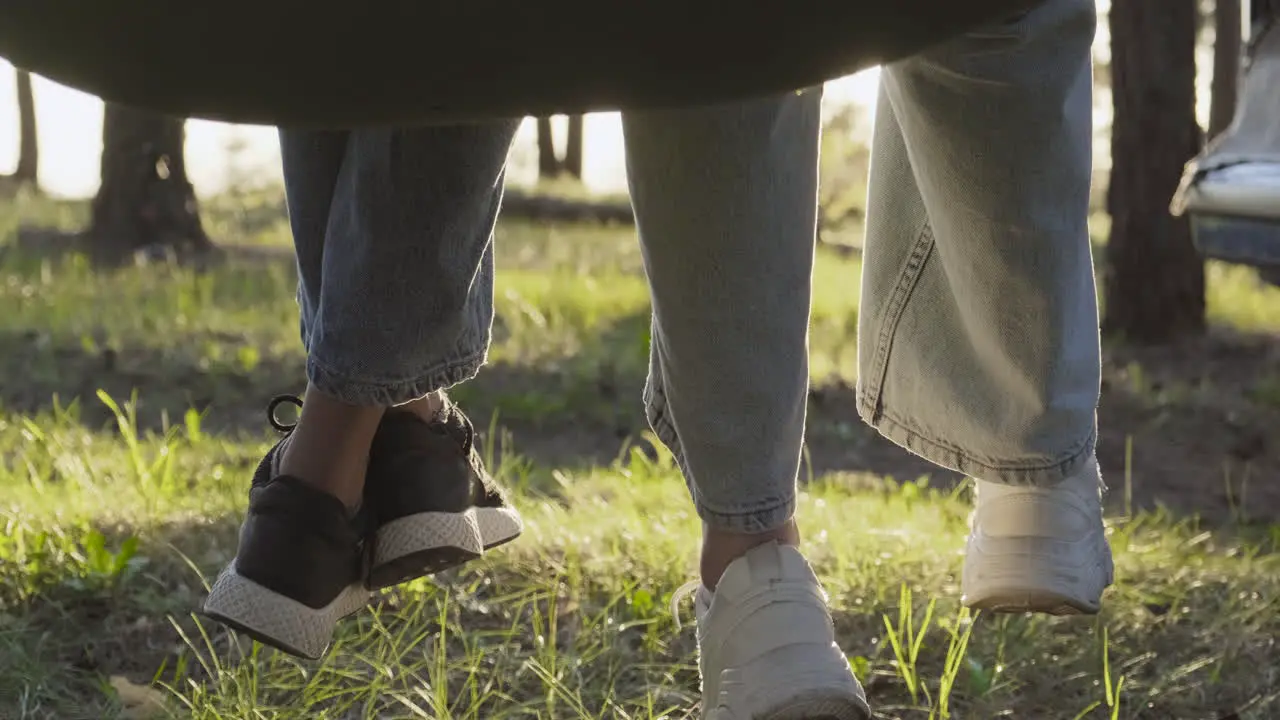 The Feet Of Two Girls Swaying In A Hammock In The Middle Of The Forest