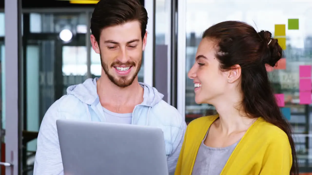 Male and female executives having discussion over laptop