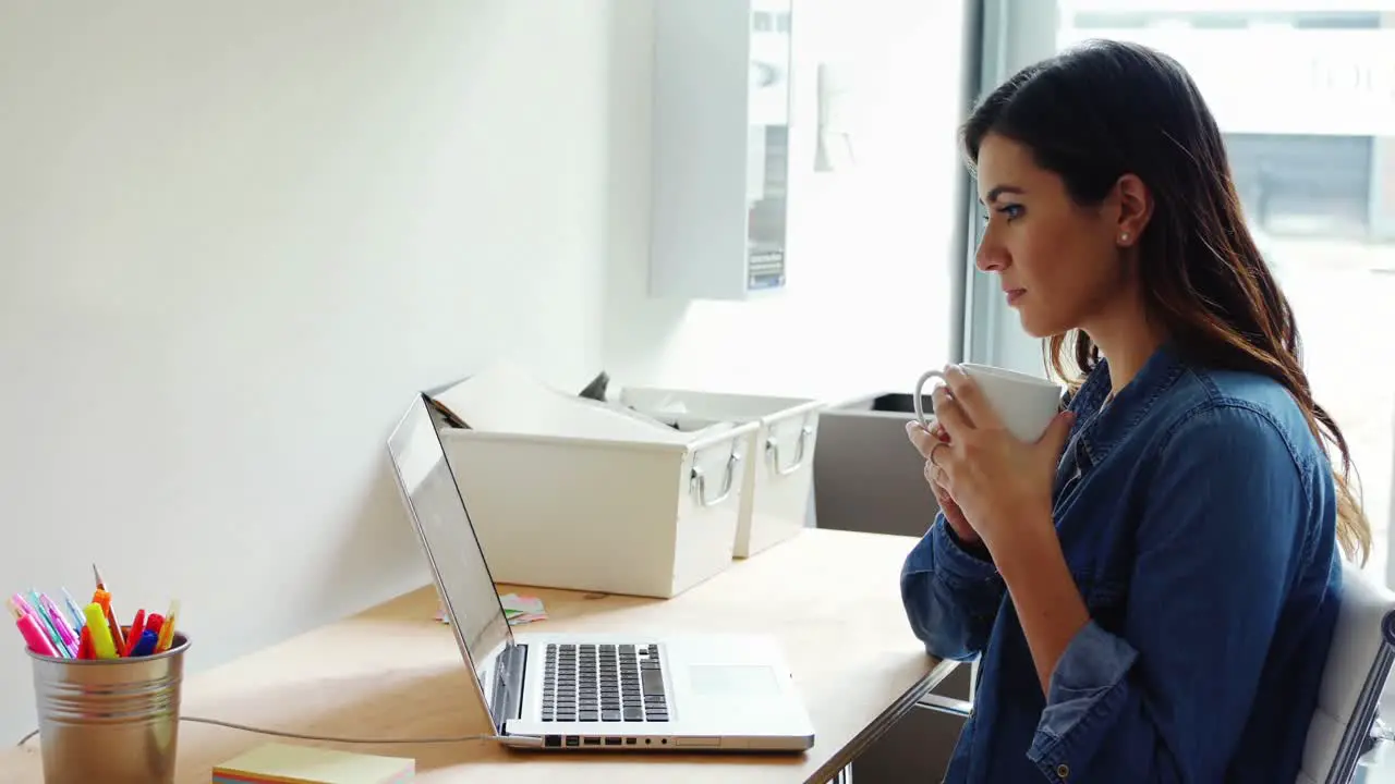 Female executive using laptop white having coffee