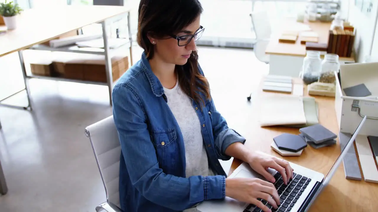 Female executive sitting at desk and using laptop