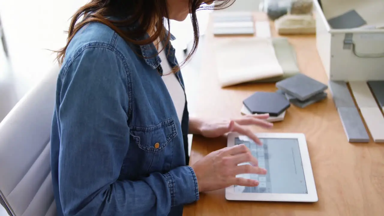 Female executive sitting at desk and using digital tablet